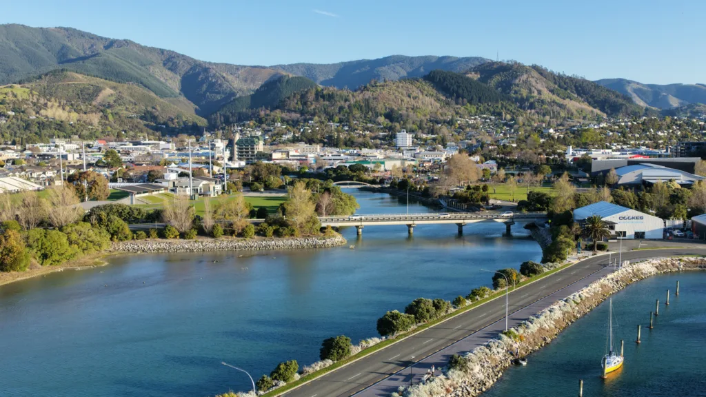 The Maitai River flowing into Nelson Haven beside the waterfront road, with Nelson city behind