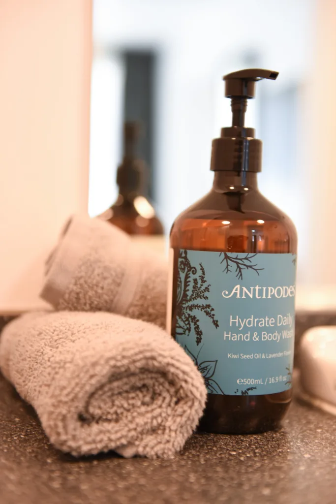 Antipodes Hydrate Daily hand and body wash beside a rolled towel