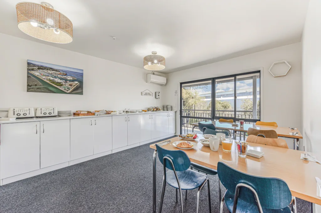 Breakfast room with complimentary continental buffet, set tables and doors to the balcony