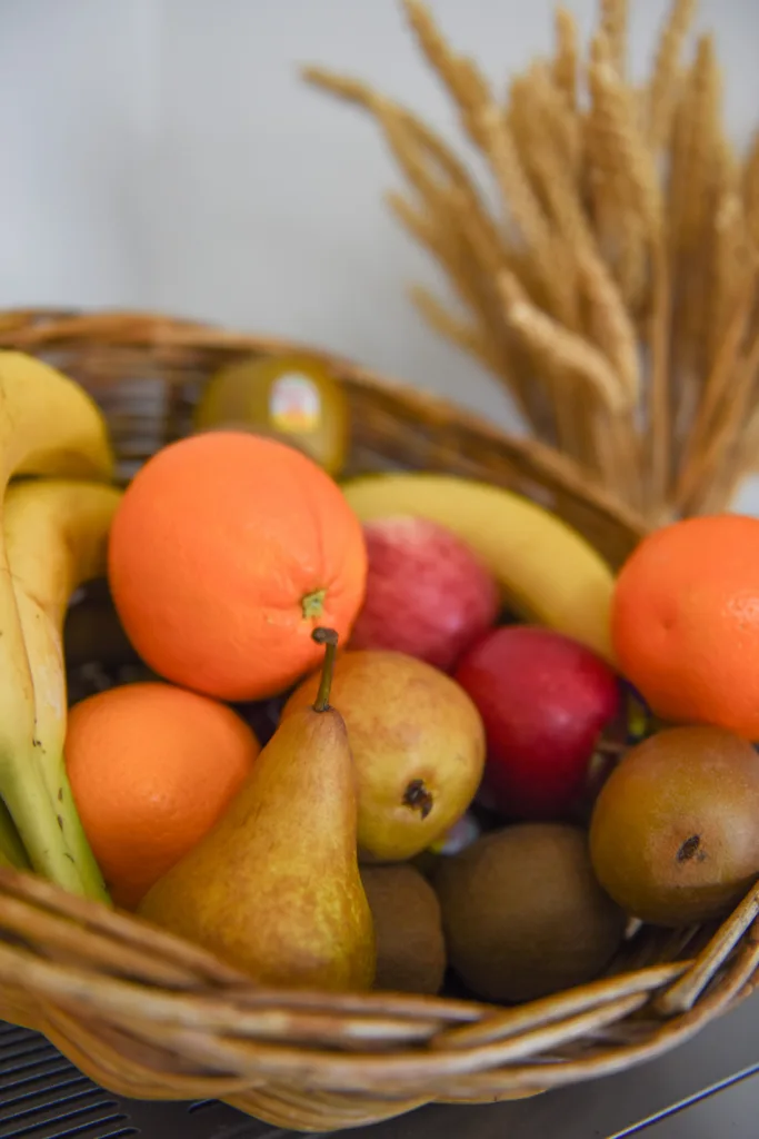 Basket of fresh fruit with oranges, apples, pears, bananas and kiwifruit on the breakfast counter