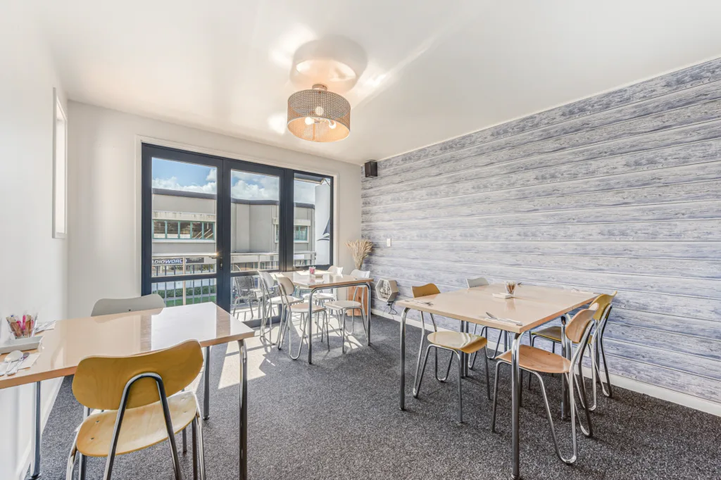 Sunny breakfast room with tables and doors opening onto patio