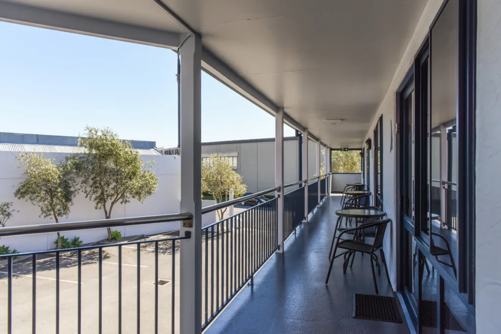 Covered upper walkway with outdoor tables and chairs outside the Courtyard Studios