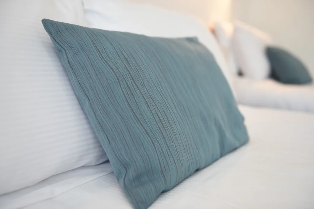 Teal cushion on crisp white bed linen