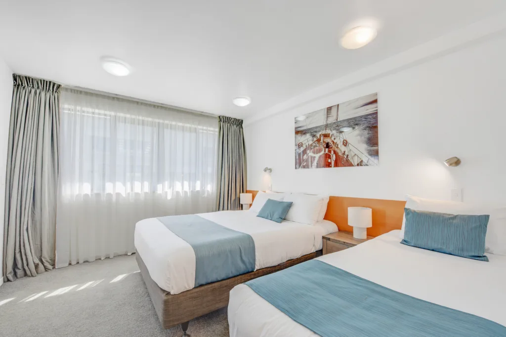 Courtyard Suite bedroom with queen and single beds and sailing artwork