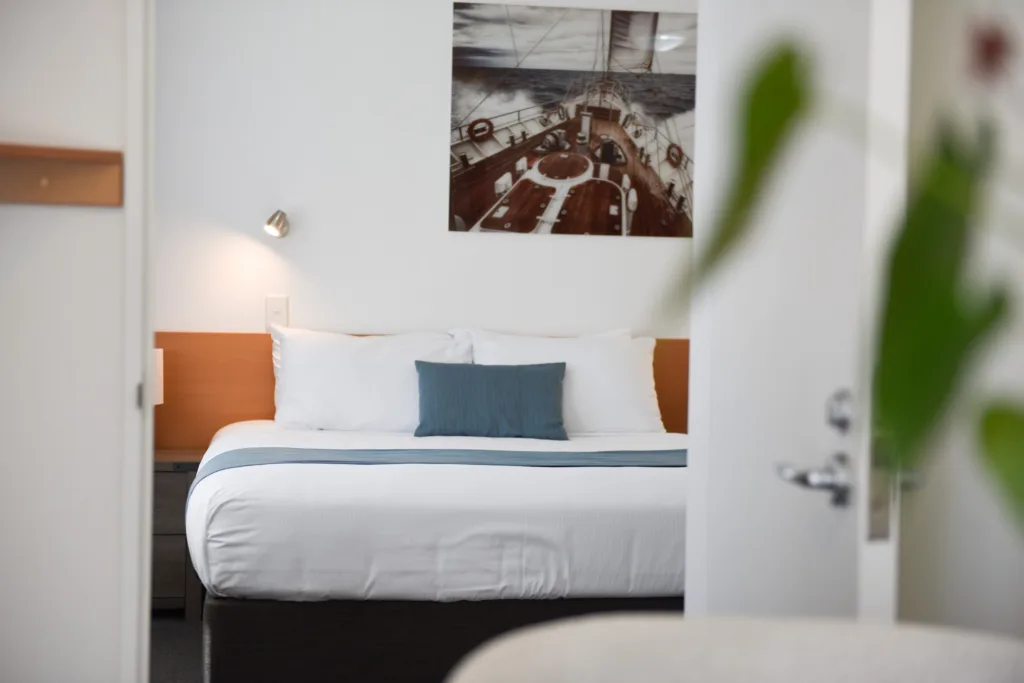 Courtyard Suite bedroom seen through the doorway, with queen bed and sailing artwork