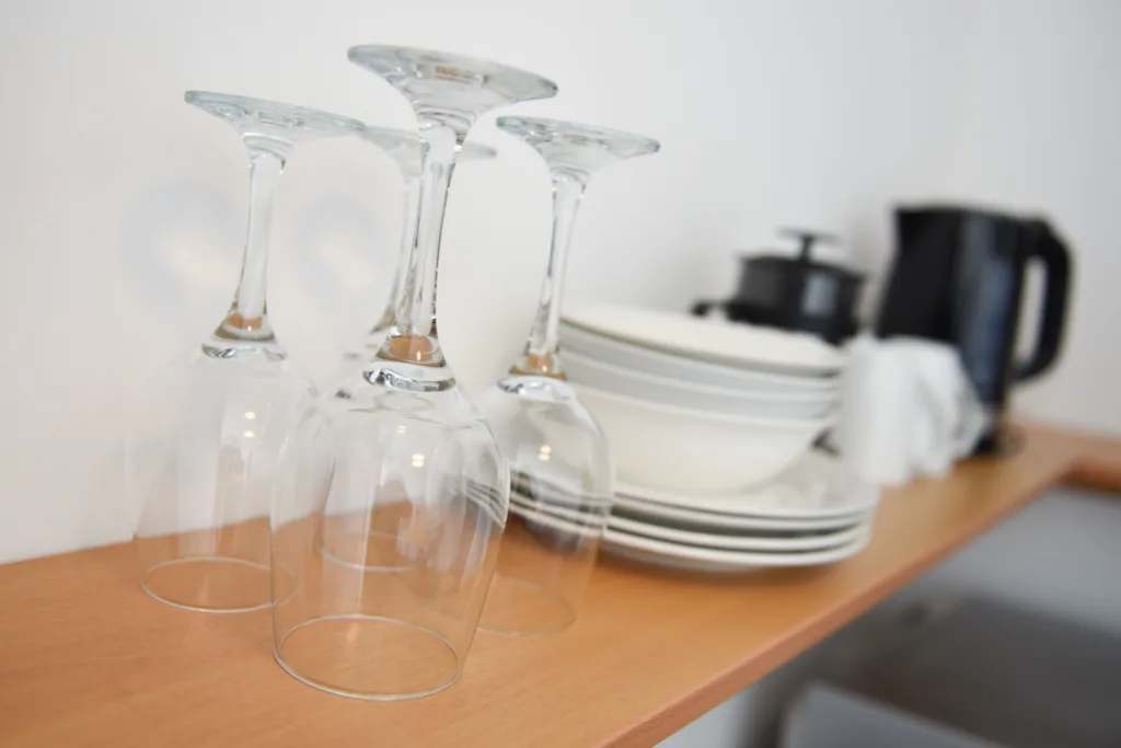 Wine glasses, plates, kettle and plunger on the kitchenette shelf