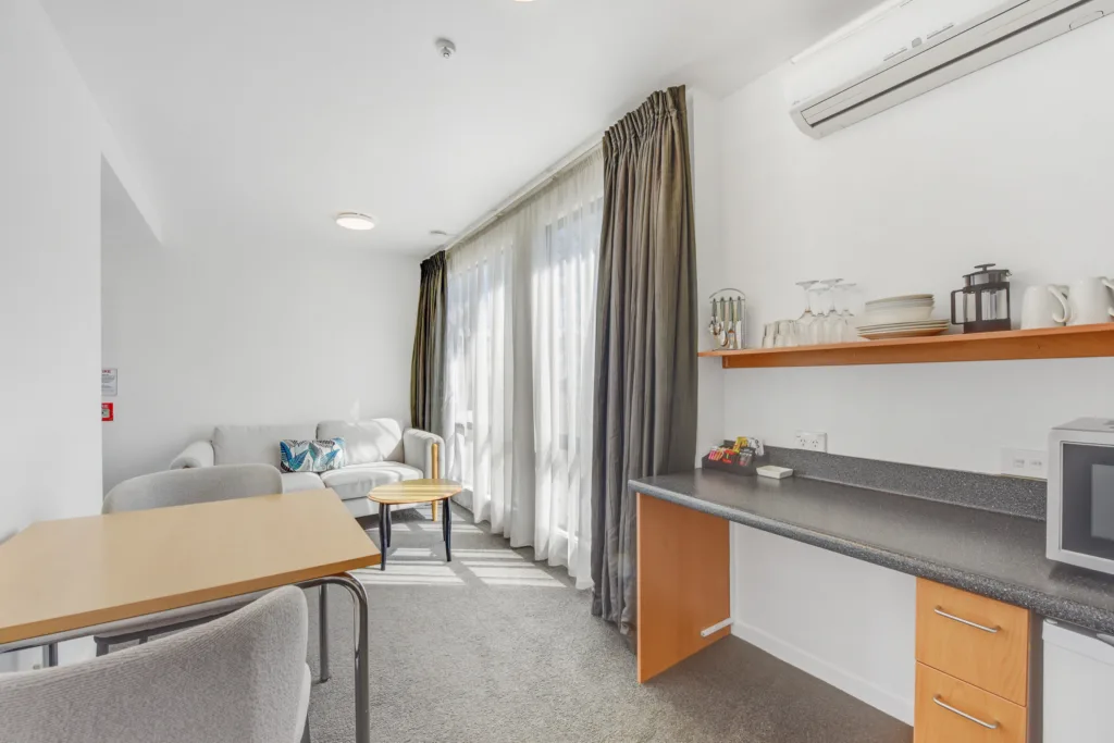 Courtyard Suite living area with sofa, dining table and kitchenette with microwave