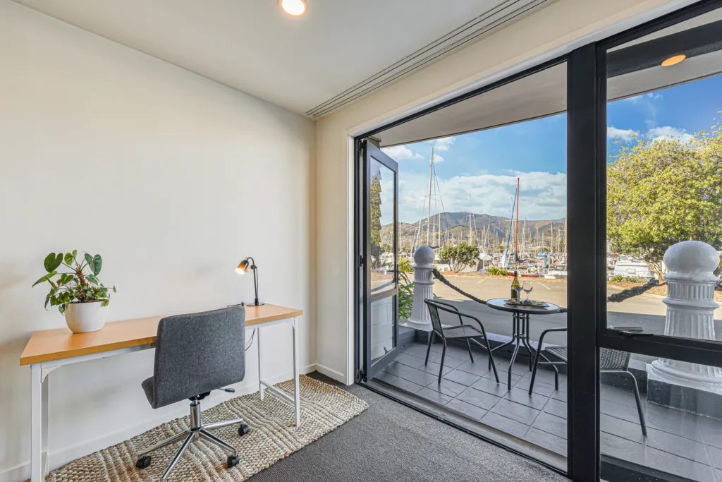 Work desk beside open doors to a private patio facing Nelson Marina