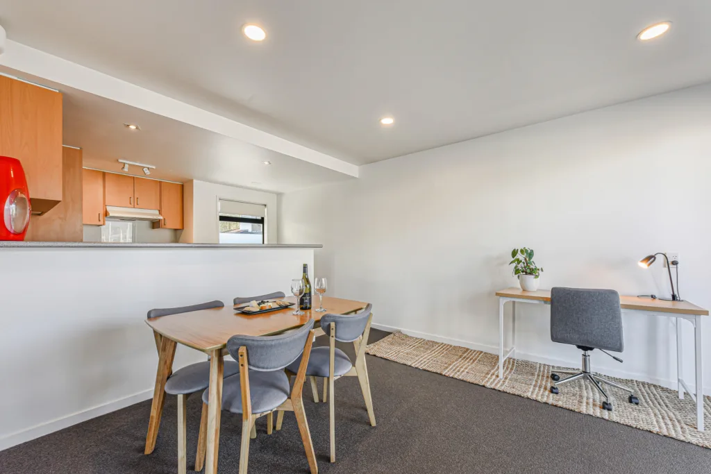 Dining table set with wine and a platter, with work desk and kitchen