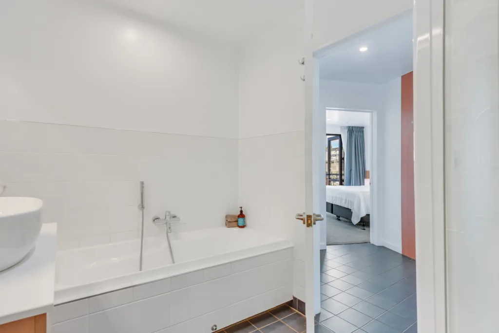 Marina View Apartment bathroom with bath, looking through to the bedroom