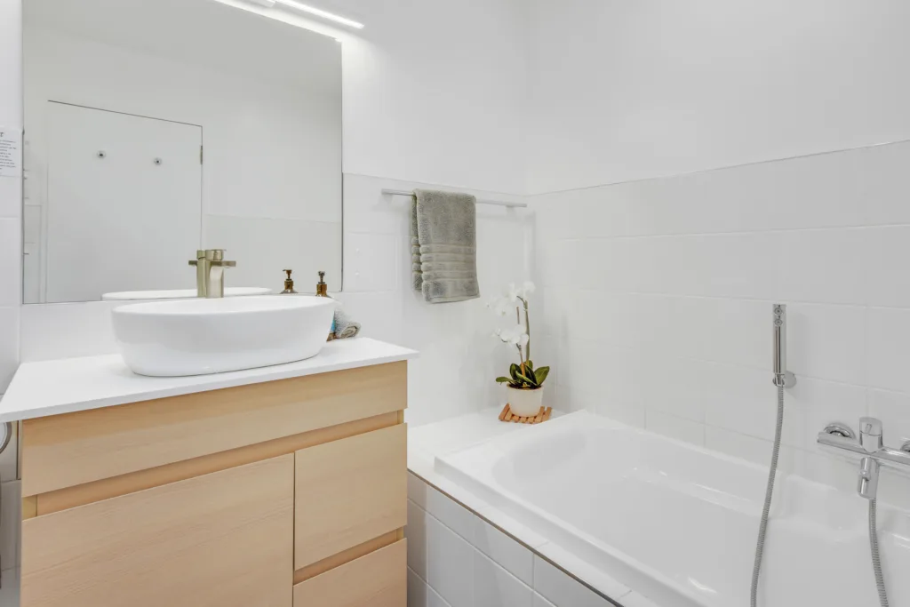 Marina View Apartment bathroom with timber vanity, vessel basin, brass tapware and bath