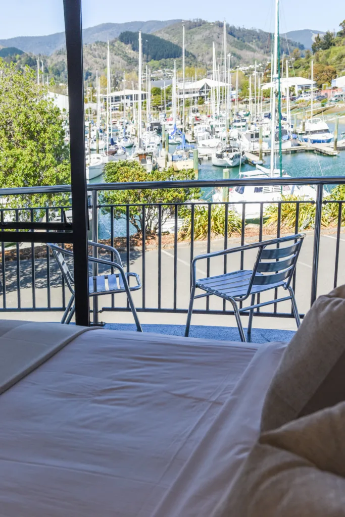 Bed facing open doors to a balcony and Nelson Marina