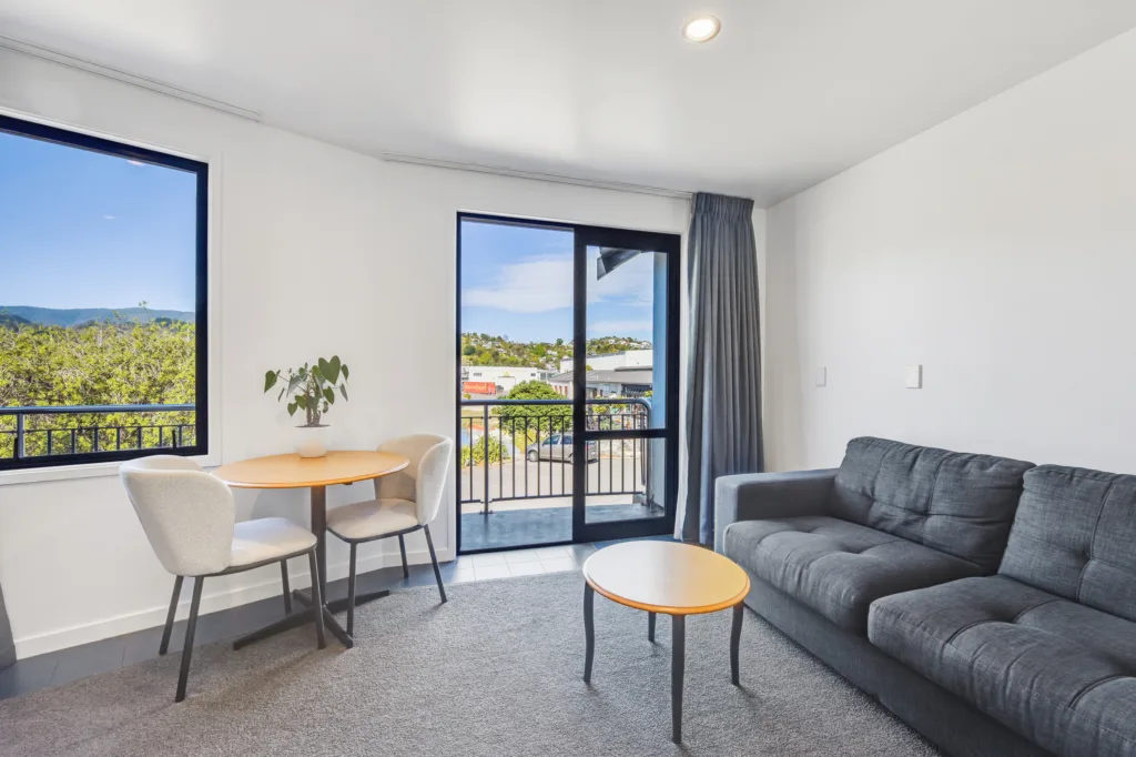 Marina View Apartment lounge with sofa, dining table and doors to a balcony
