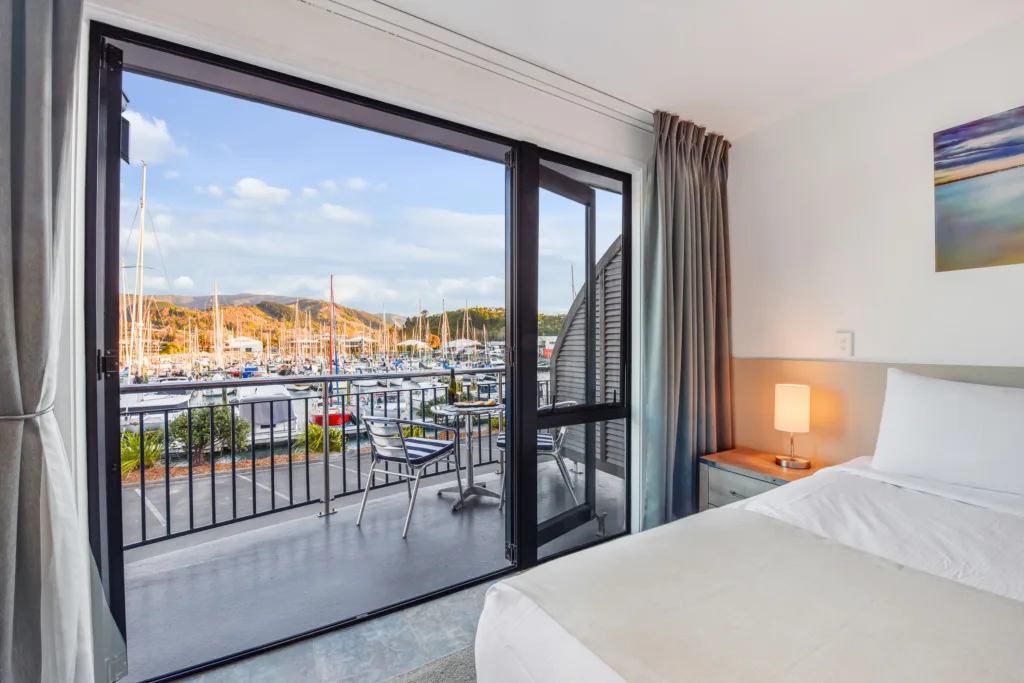 Marina View Studio view from the bed to a balcony overlooking Nelson Marina