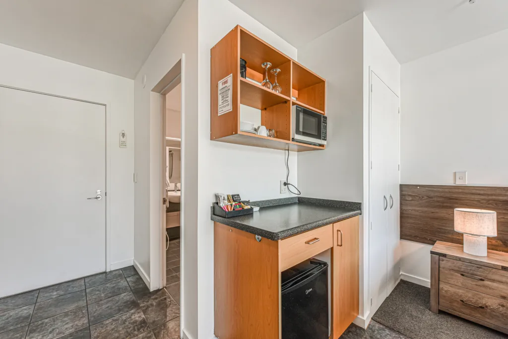 Kitchenette with microwave, bar fridge and glassware beside the entry and ensuite